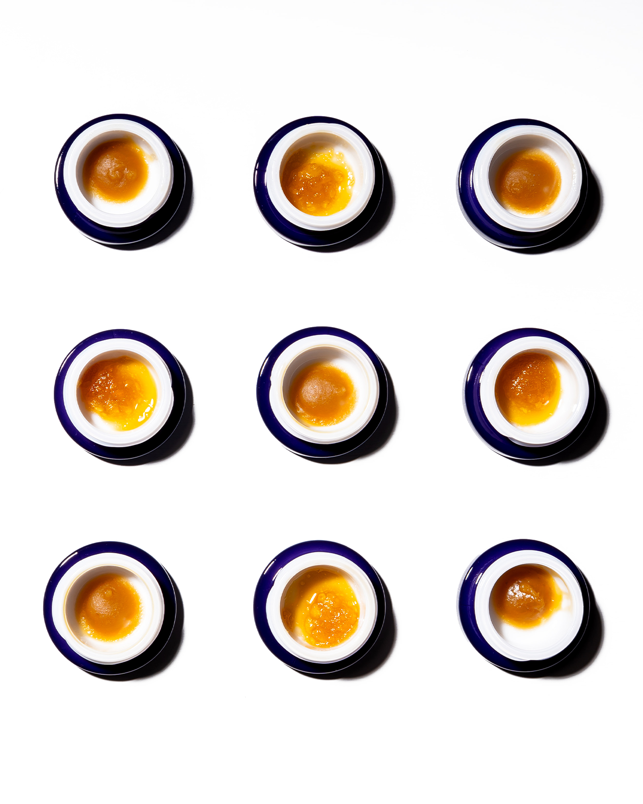 9 jars of infinity wax are lined up in a grid with the lids off showing the concentrates inside.