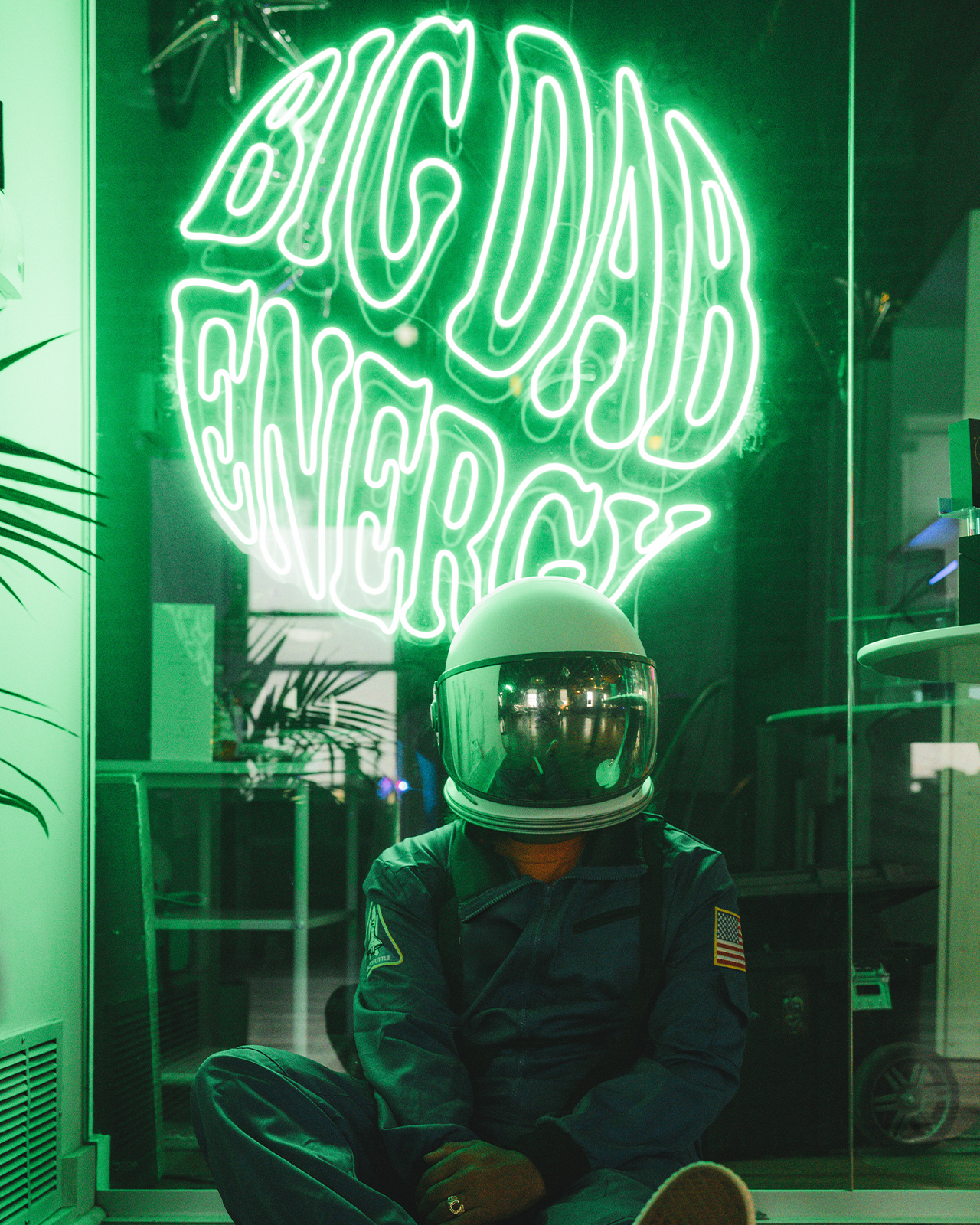 A person in a space suit against a neon sign that reads big dab energy